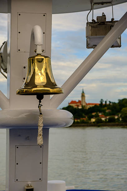 Bronze bell on the deck of a ship. In the background you can see Wallsee Castle in Wallsee-Sindelburg. Austria