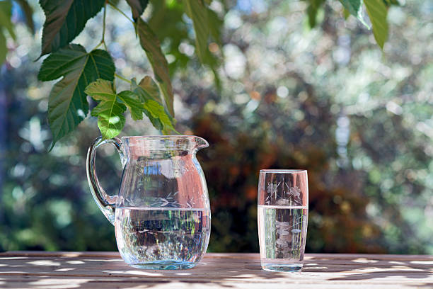 pitcher and glass of water on a wooden table. the back garden. Copy space