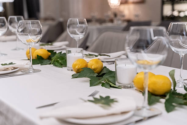 istock beautiful table decoration in restaurant. festive table setting in restaurant. white tablecloth on table, wine glasses, white plates, lemons, candles are burning. romantic atmosphere 2211102841