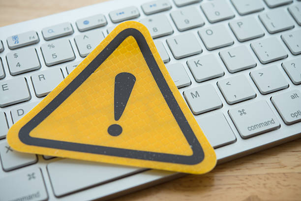 istock Yellow alert sign on white keyboard on wooden table background. 2211105063