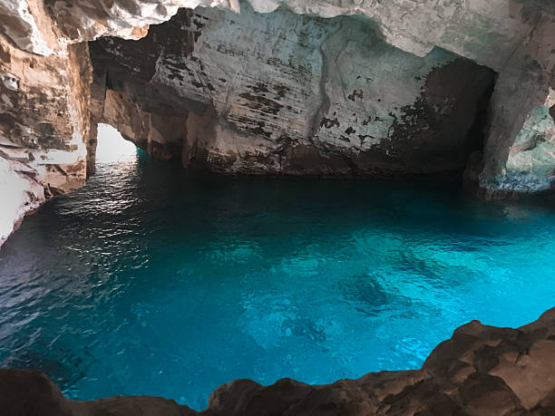 istock Blue water glows inside a rocky cave, exposing a secret channel to open sea. 2211107743