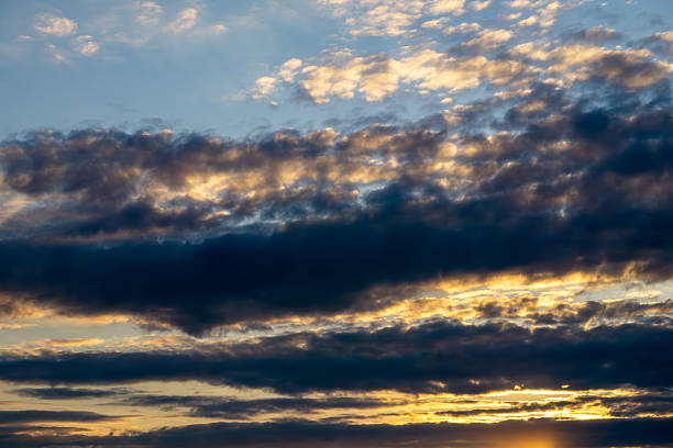 Dramatic sky at sunset, with dark clouds and golden light shining through