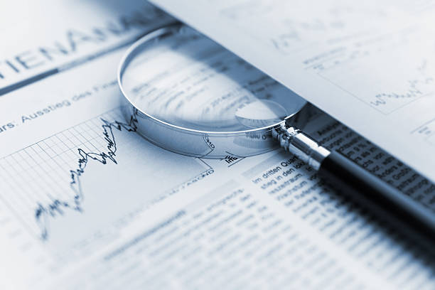 istock Magnifying glass on stock chart financial data 2211121068