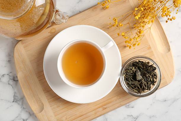 istock Refreshing green tea and dry leaves on white marble table, flat lay 2211125255