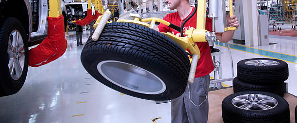 istock Worker assembling tires on trucks in a manufacturing plant during daytime operations 2211125509