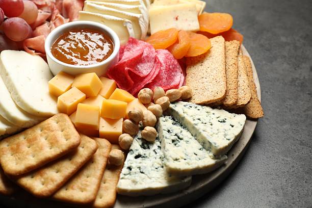 istock Different types of cut cheese and other snacks on grey textured table, closeup 2211127205