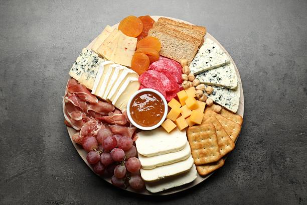 istock Different types of cut cheese and other snacks on grey textured table, top view 2211127276