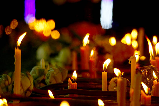 Soft candlelight illuminates lotus flowers in a tranquil setting. This image captures the essence of spirituality and reflection, perfect for memorial events.