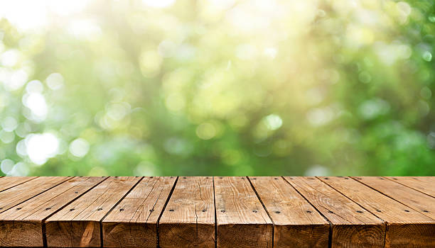 istock Empty old wooden table with fresh green spring theme in background 2211130503