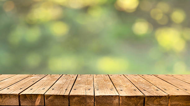 istock Empty old wooden table with fresh green spring garden in background 2211130720