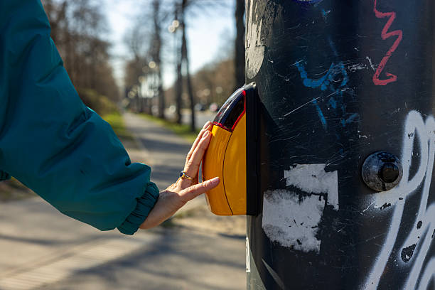 A pedestrian presses the crossing button on the traffic light pole to change the signal