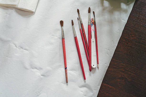 Various paintbrushes and a canvas on white paper - art equipment on table covered with white paper - arts and crafts, hobby