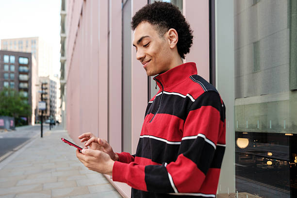 istock Young man using mobile phone in urban setting, smiling and browsing social media 2211138622