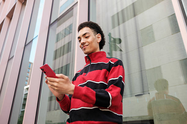 Young man using smartphone in front of modern building