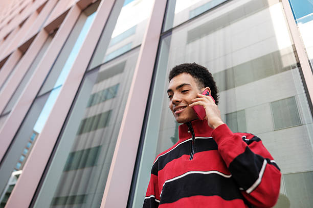 istock Young man talking on the phone in front of modern building 2211138633