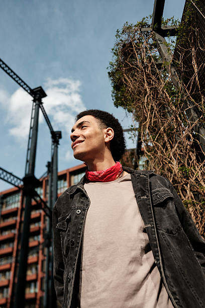 istock Young man smiling and looking up in urban setting with red bandana 2211138663