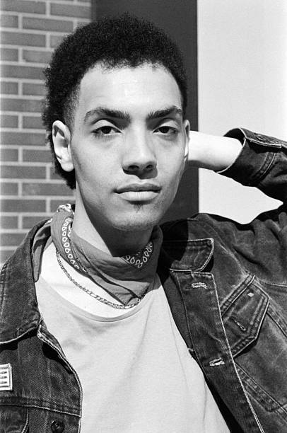 istock Young man wearing bandana and denim jacket, posing with hand on head 2211138823