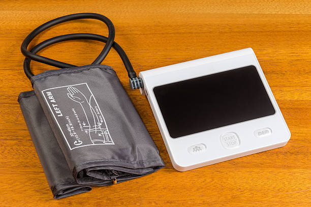 Electronic automatic medical sphygmomanometer, consisting of the measuring unit and  inflatable cuff lie on a wooden table