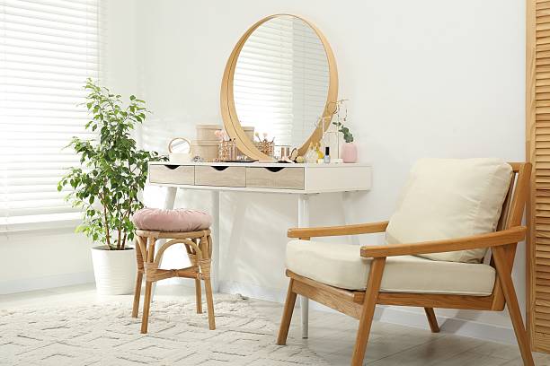 istock Makeup room. Dressing table with mirror, different beauty products, stool, armchair and houseplant indoors 2211143493