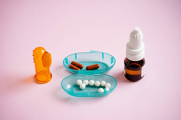 A vibrant blue container that is filled to the brim with various pills, alongside a bottle of liquid drops, all positioned on a striking pink surface, creating a visually appealing scene