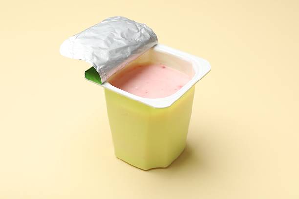 Delicious yogurt in plastic cup on beige background, closeup