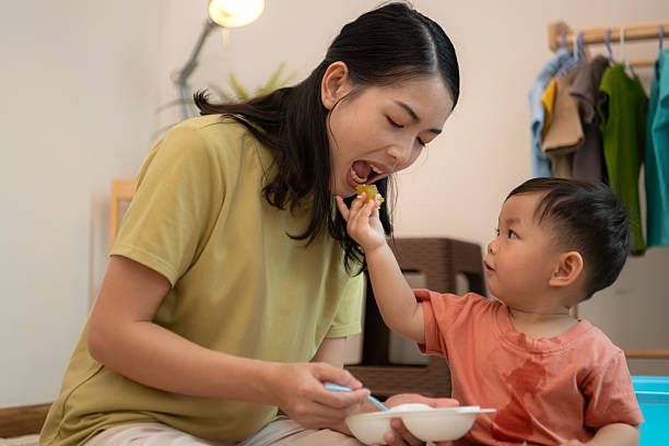 Little boy with breakfast with mom feeding him before bathing