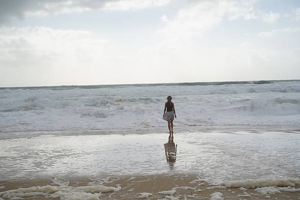 istock Woman Gazing at Ocean Waves on a Cloudy Day 2211145212