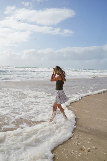 istock Woman Walking Along the Beach with Waves and Foam 2211145214