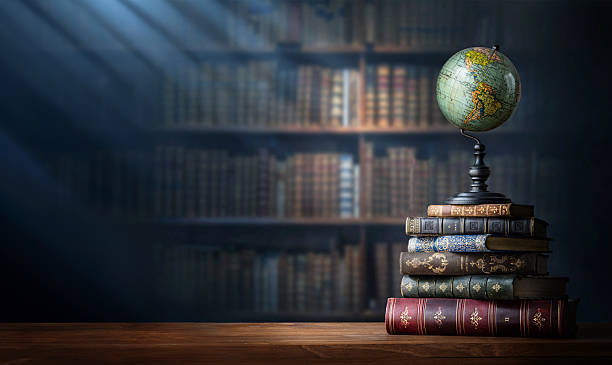 istock Old geographical globe and old book in cabinet with bookselfs. Science, education, travel background. History and geography team. Ancience, antique globe on the background of books. 2211148813