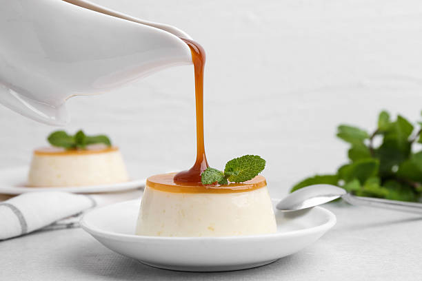 istock Pouring caramel sauce onto tasty pudding on white table, closeup 2211149837