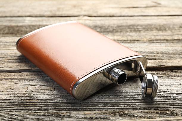 istock One hip flask on wooden table, closeup 2211150343