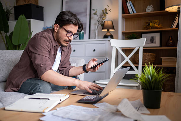 istock Young man holding phone and typing on laptop. 2211151491
