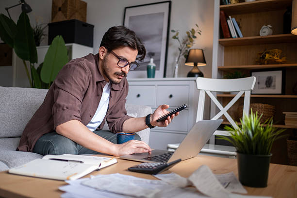 istock Young man holding phone and typing on laptop. 2211151493