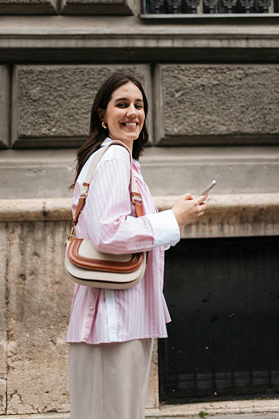 istock Smiling young woman using smartphone walking in the city 2211153729