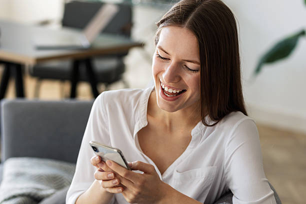 istock Happy young woman using mobile phone home 2211159737