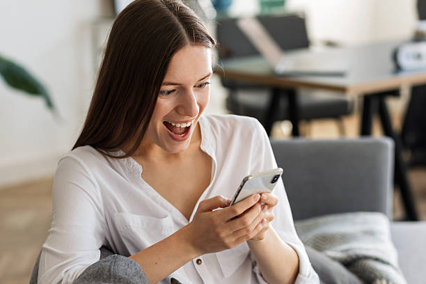 istock Excited woman using smartphone at home smiling 2211159740