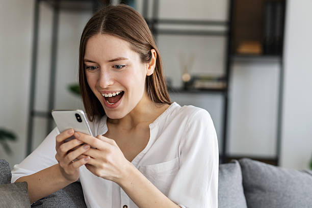 istock Excited woman using smartphone at home smiling 2211159753