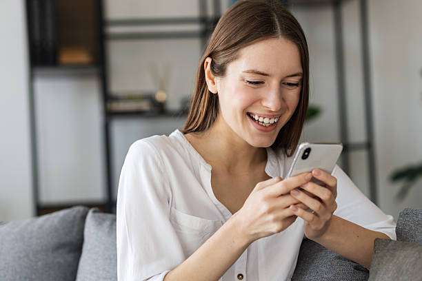 istock Happy young woman using mobile phone home 2211159754