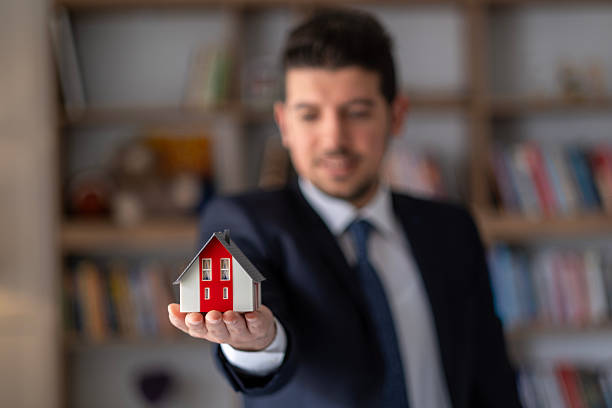 istock Business man hand hold the house model saving small house 2211164373