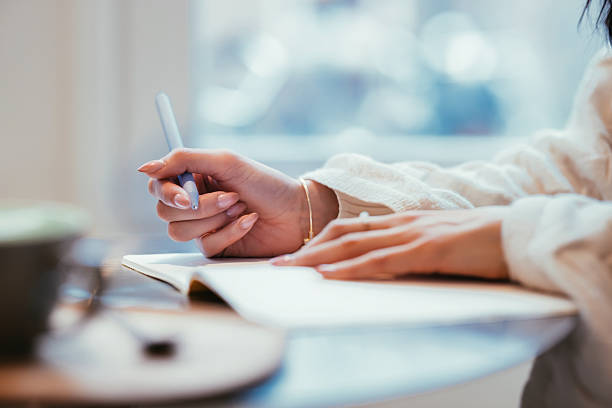 Woman Writing in Journal on Table with Pen and Soft Lighting