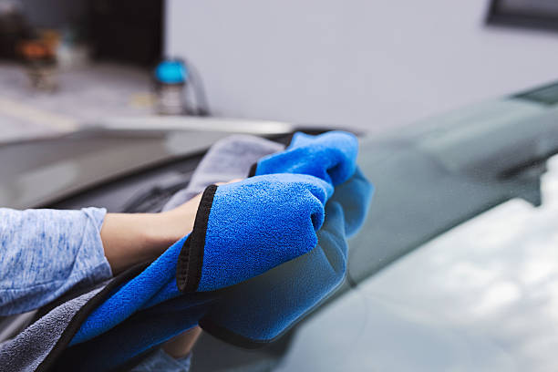 istock Person Cleaning Car Windshield With Blue Microfiber Cloth Outdoors 2211167783