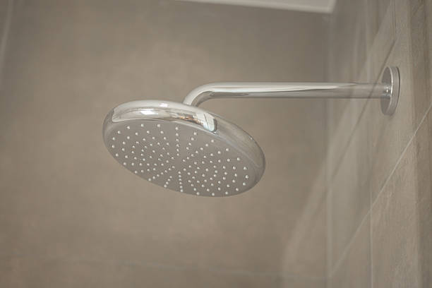 istock A modern chrome showerhead with multiple nozzles is mounted on a tiled wall in a bathroom, featuring a sleek design and beige tiles, creating a clean and minimalist look. 2211168163
