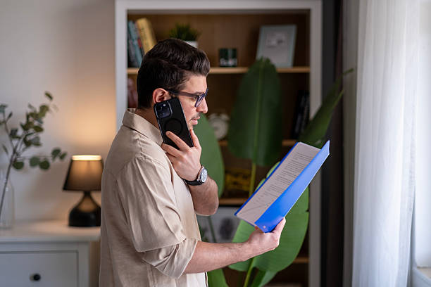 istock He is both talking on the phone and reviewing documents. 2211170354
