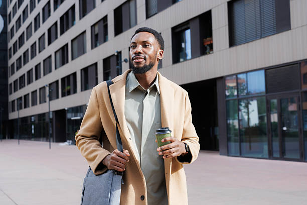 istock Man in a coat holding coffee while walking in an urban area 2211170369