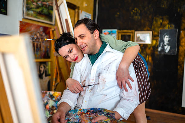 Mid adult artist with his wife working on his painting in a studio
