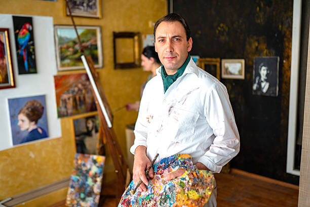 Mid adult artist with his wife working on his painting in a studio