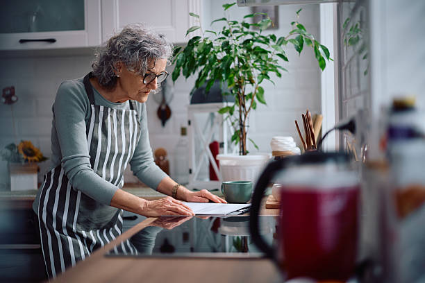 istock Senior woman going through her home finances in the kitchen. 2211174495