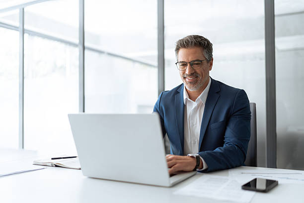 istock Mature Indian or Latin hispanic business man ceo manager using laptop computer typing in modern office. Middle eastern smiling senior businessman entrepreneur sitting at desk working on pc. Copy space 2211175041