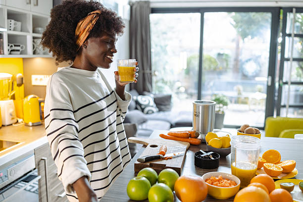 istock Woman enjoying fresh orange juice in a bright, modern kitchen 2211175974