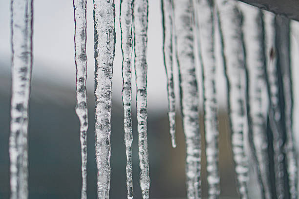 istock Close-up of densely packed icicles hanging from a surface, with translucent, pointed ends in an outdoor setting during daylight hours 2211184513